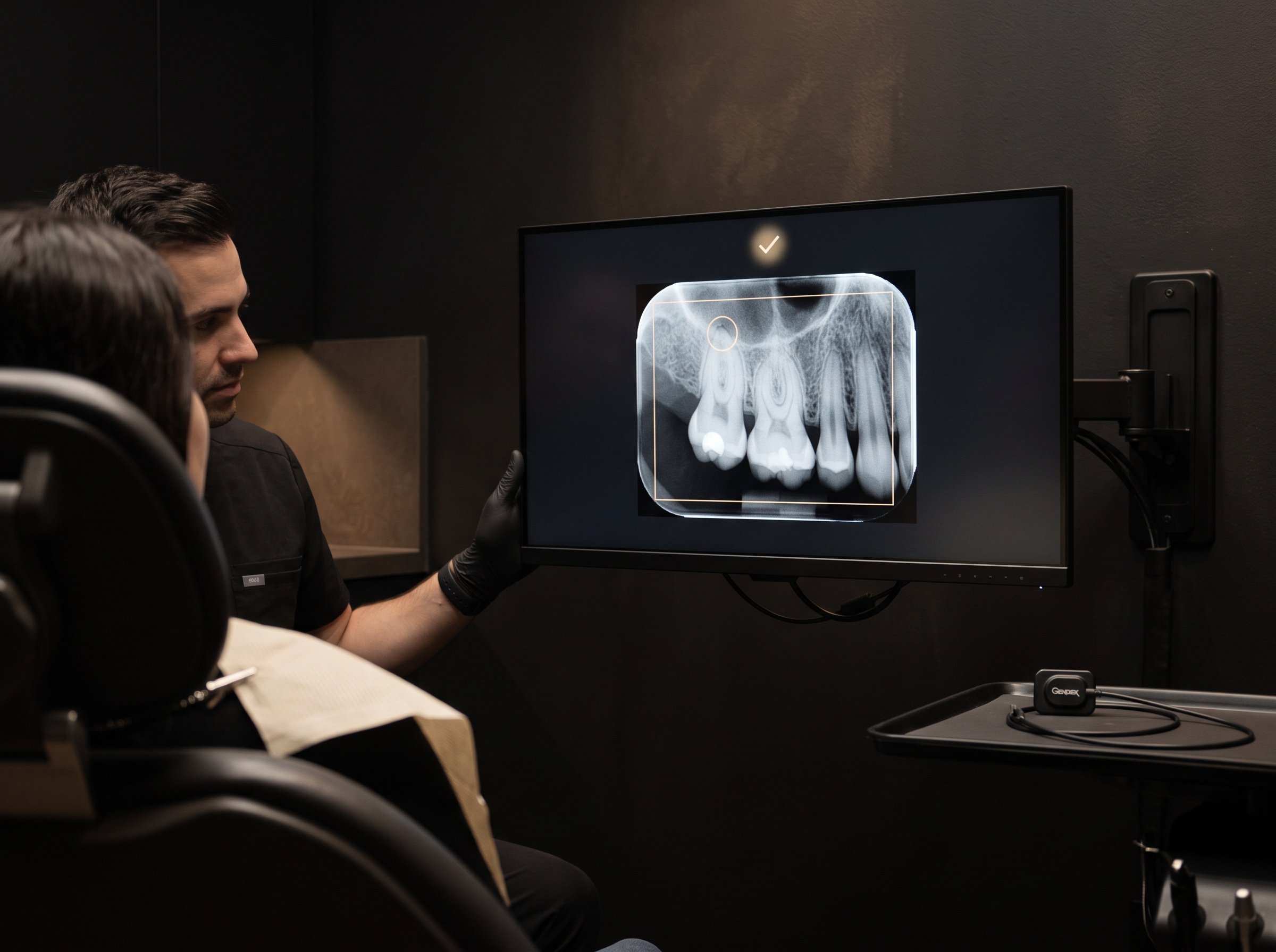 A chairside monitor showing a just-captured radiograph with a calm real-time approval indicator and framing overlay